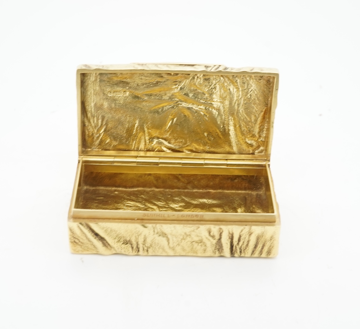 Dunhill, an attractive 9ct gold and sapphire snuffbox, circa 1973, the rectangular box of samorodok finish, the hinged lid set with a foil-backed oval sapphire, measuring approximately 5.1 x 2.7 x 1.6cm, signed Dunhill L
